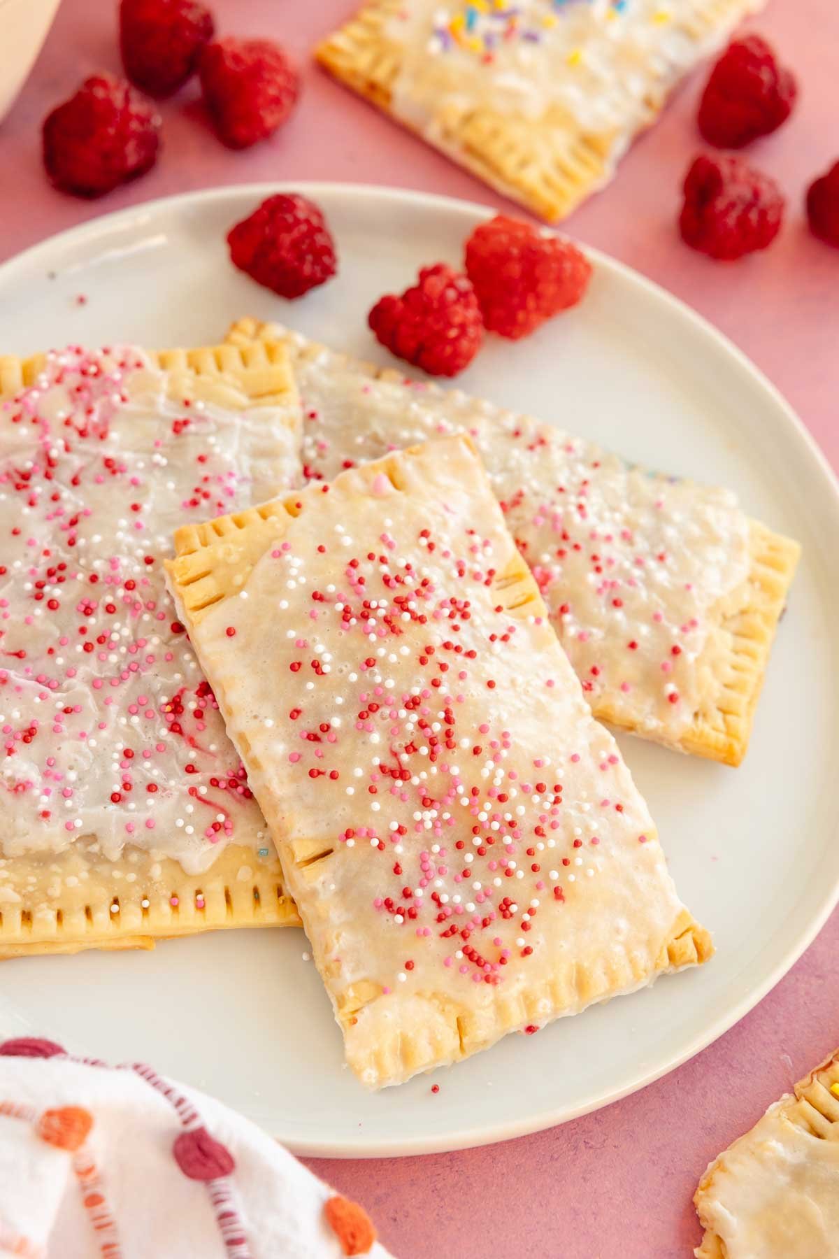 Four homemade strawberry pop tarts on a white plate