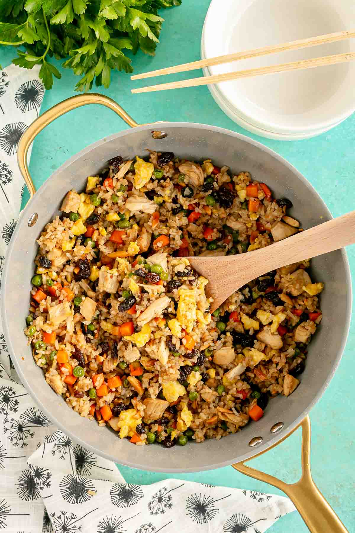 a pan with rotisserie chicken fried rice and a wooden spoon