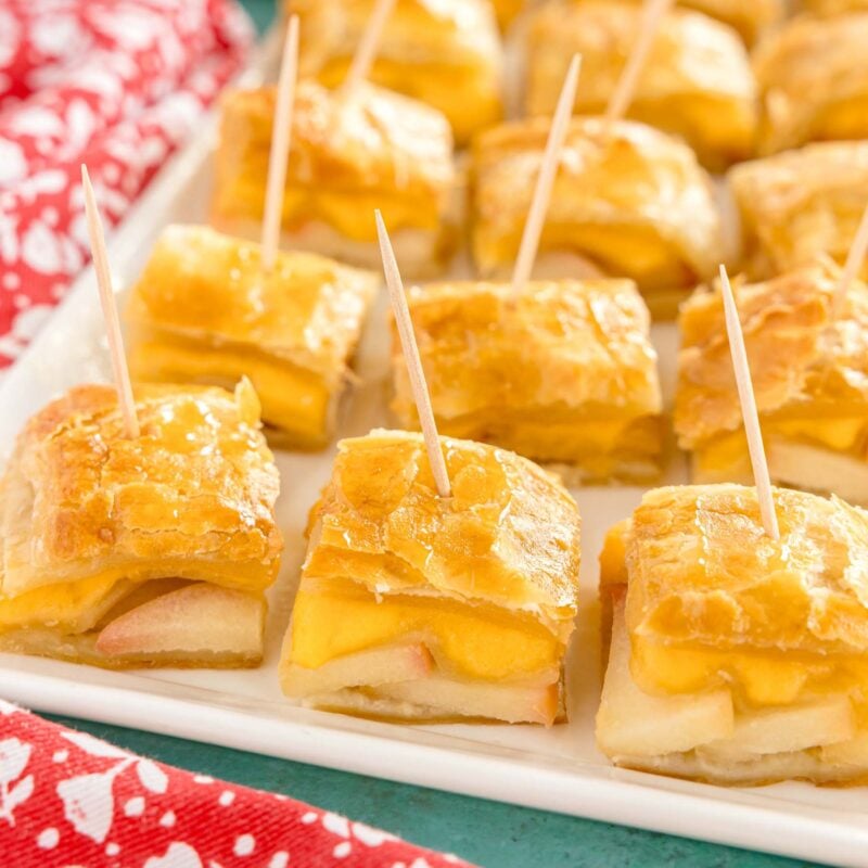 white plate with apple cheddar puff pastry bites with toothpicks in them