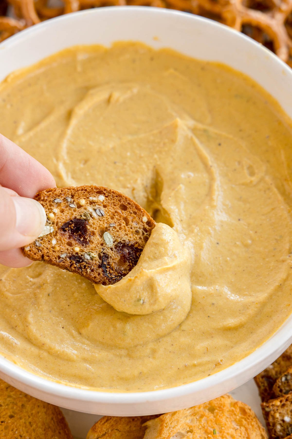 rye cracker dipped into a pumpkin goat cheese dip