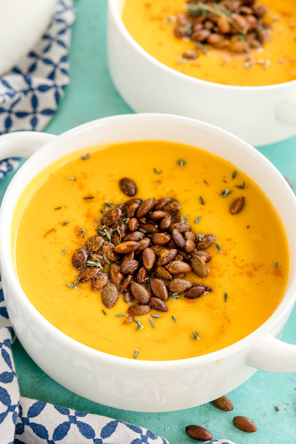 white bowl with creamy butternut squash soup with spiced pepitas sprinkled on top