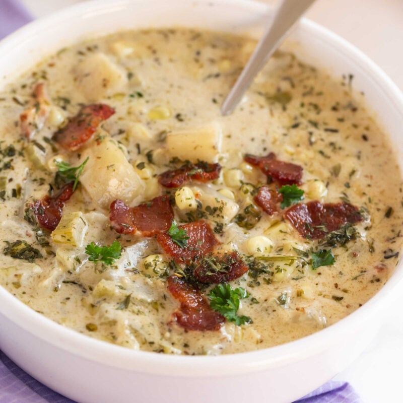 white bowl with potato and corn chowder and a spoon