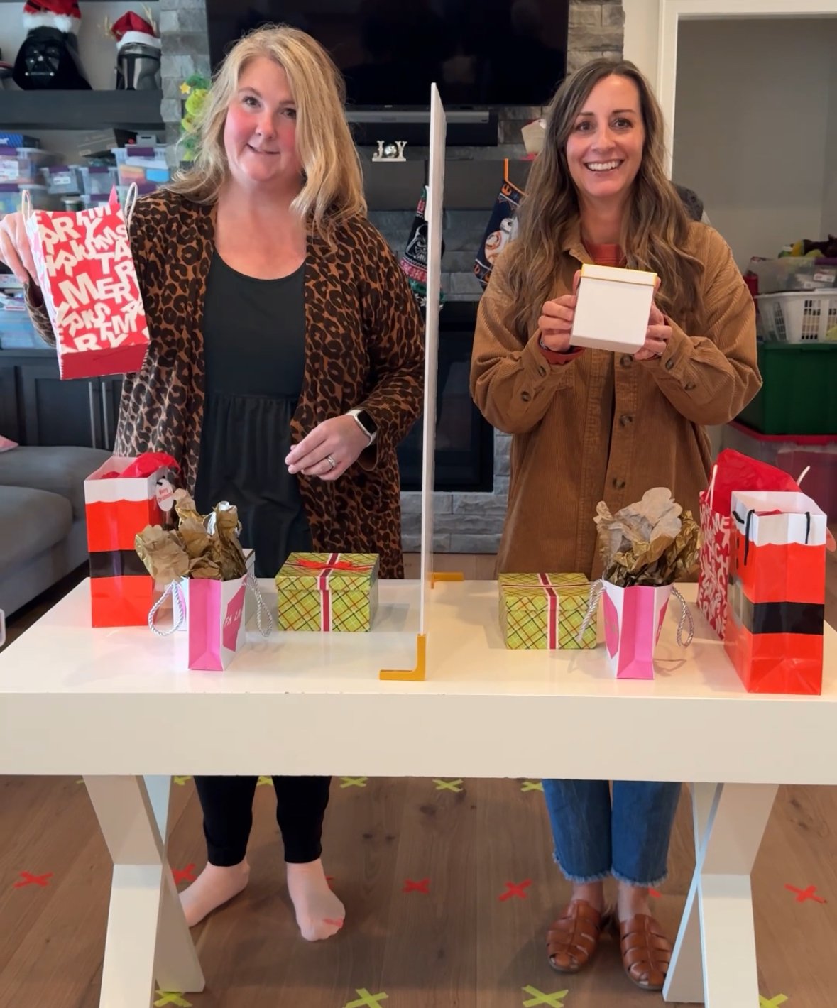 two women standing on ends of a table holding up gifts