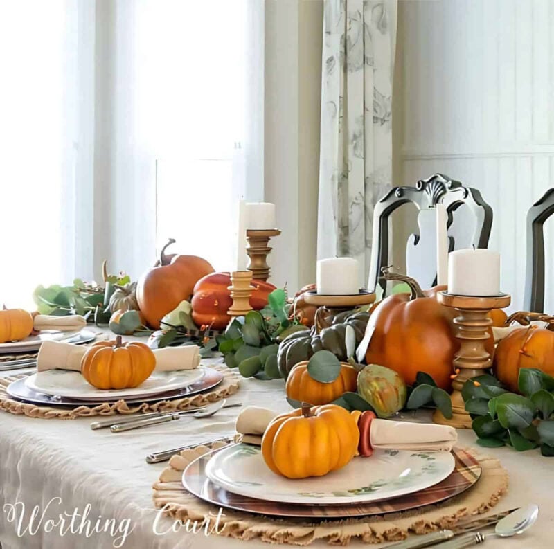 table setting with pumpkins and greenery