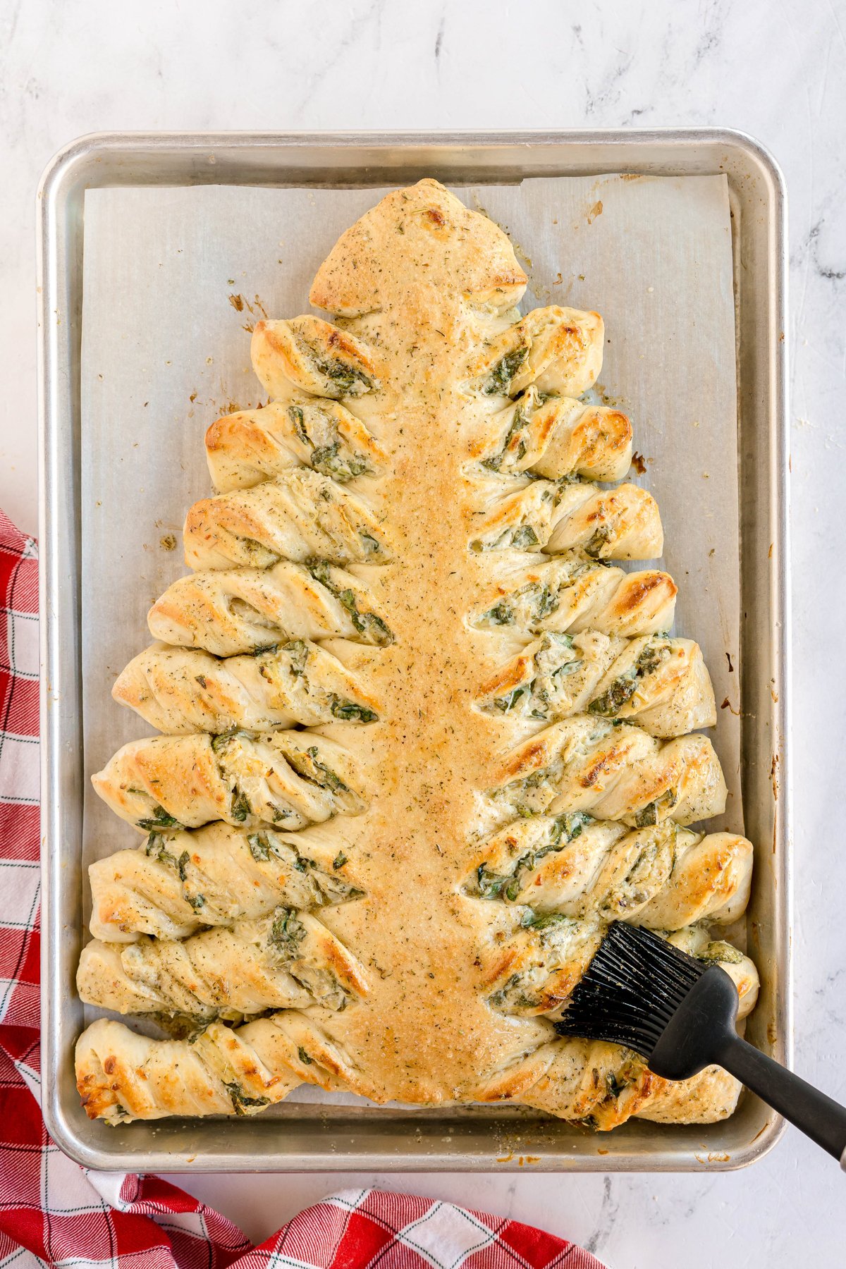 brushing a spinach artichoke christmas tree with melted butter