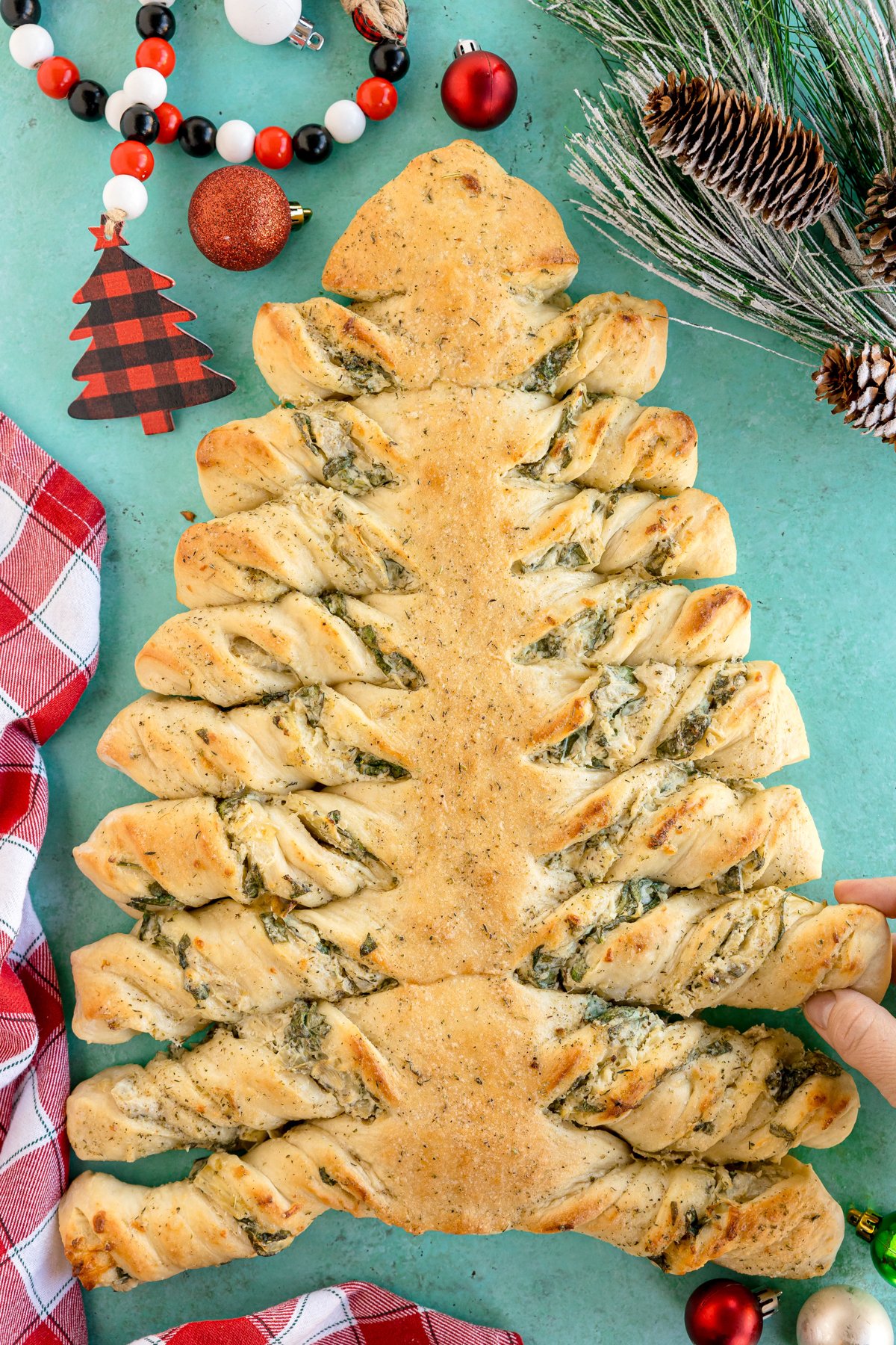 hand grabbing a piece of a spinach artichoke tree