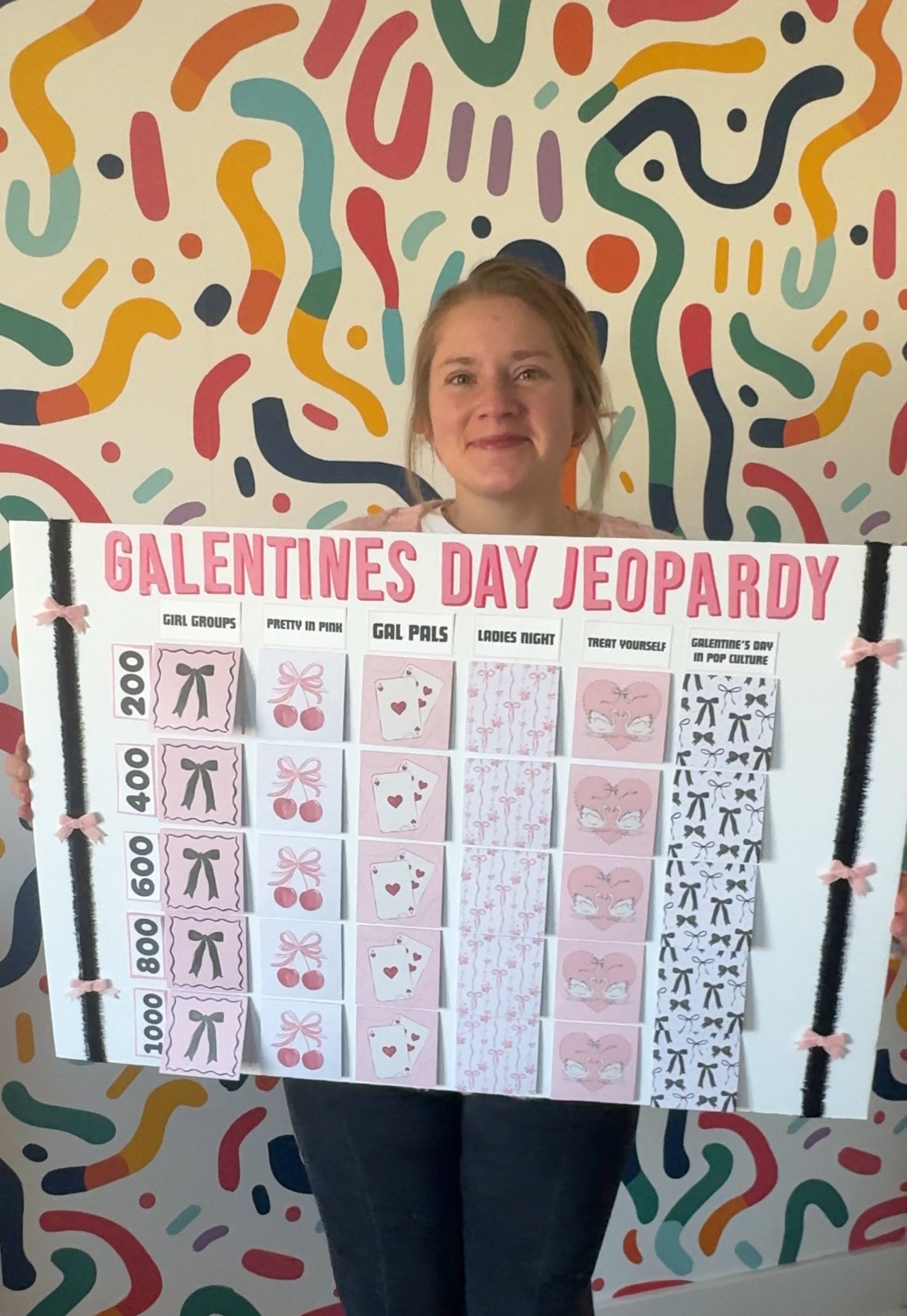 woman holding a Galentine's Day Jeopardy board