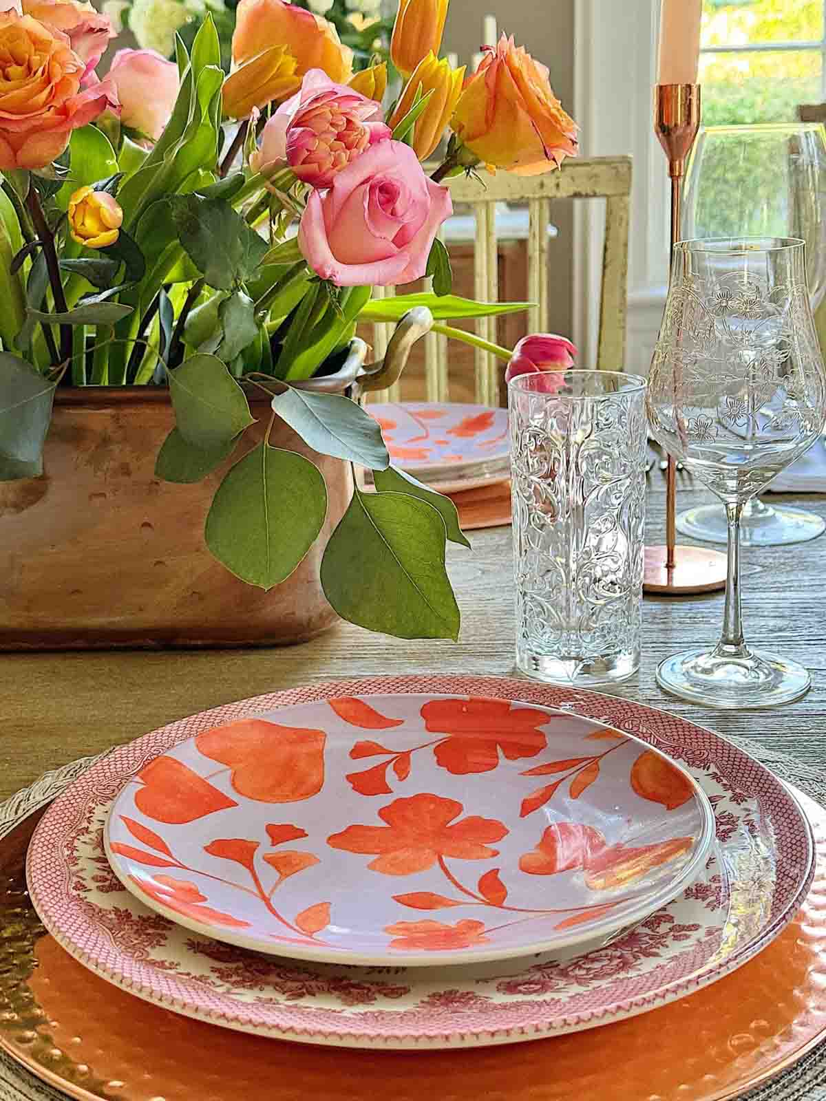 different floral plates stacked on a table with fresh flowers
