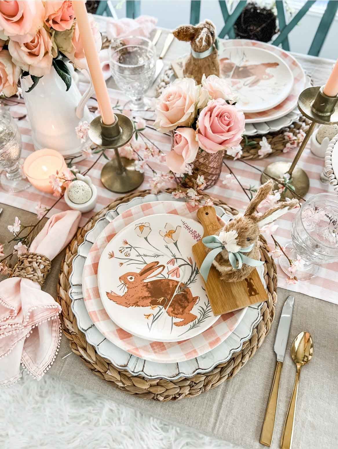 Easter table setting with pink flowers and napkins, and a colorful bunny plate