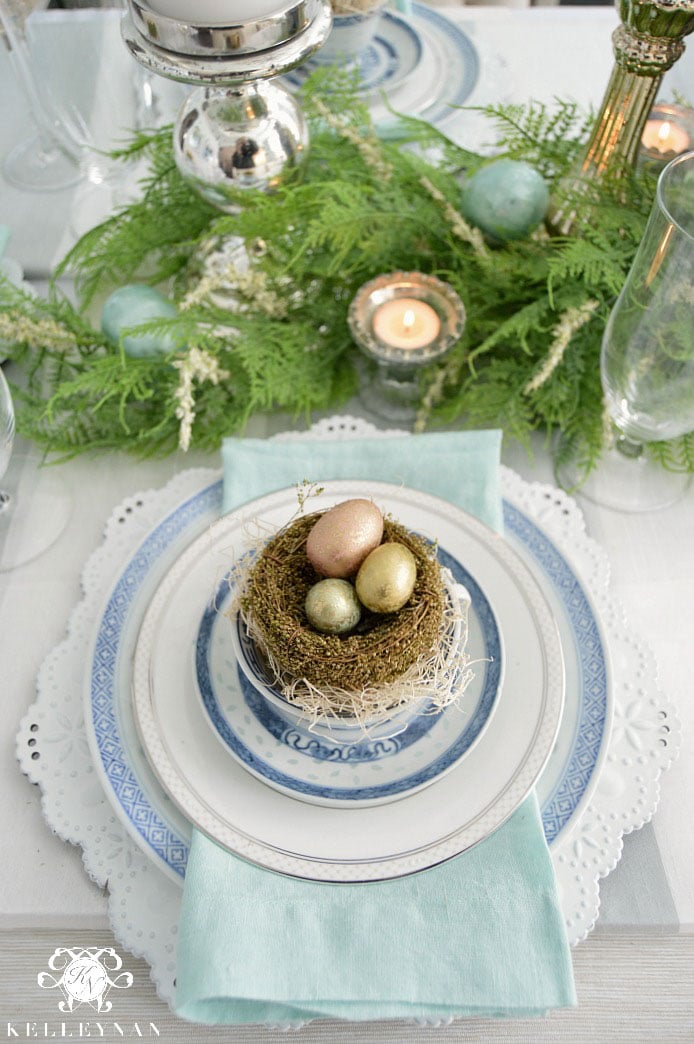 blue table setting with a bird nest filled with painted eggs