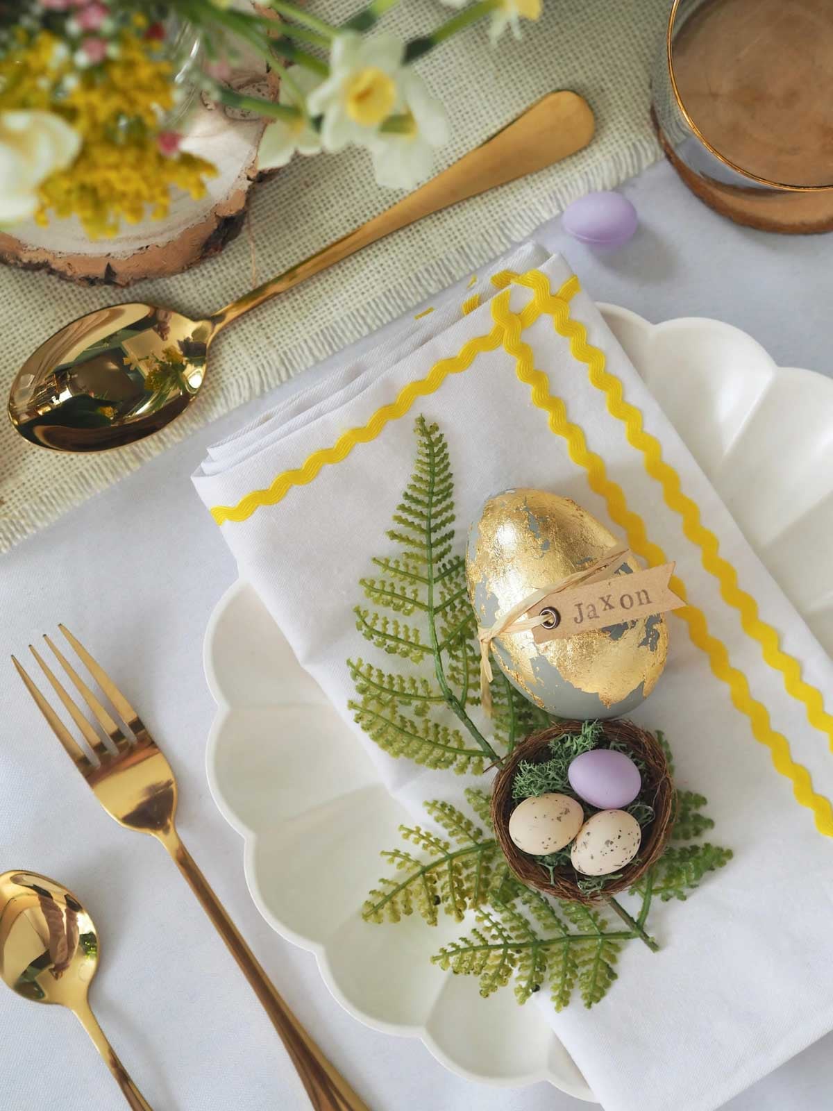 golden egg with name tag on a white plate with greenery