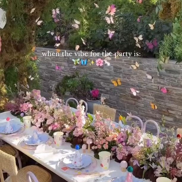 dinner table set up with butterflies hanging above it and lots of flowers