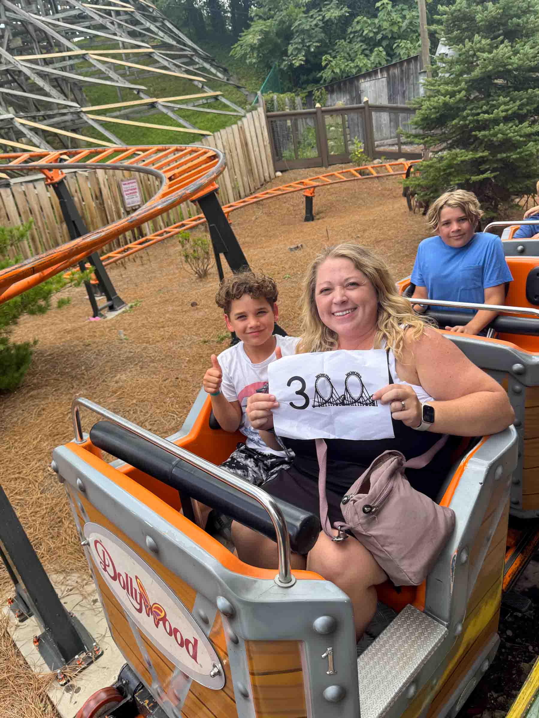 woman holding a 300 sign on a roller coaster