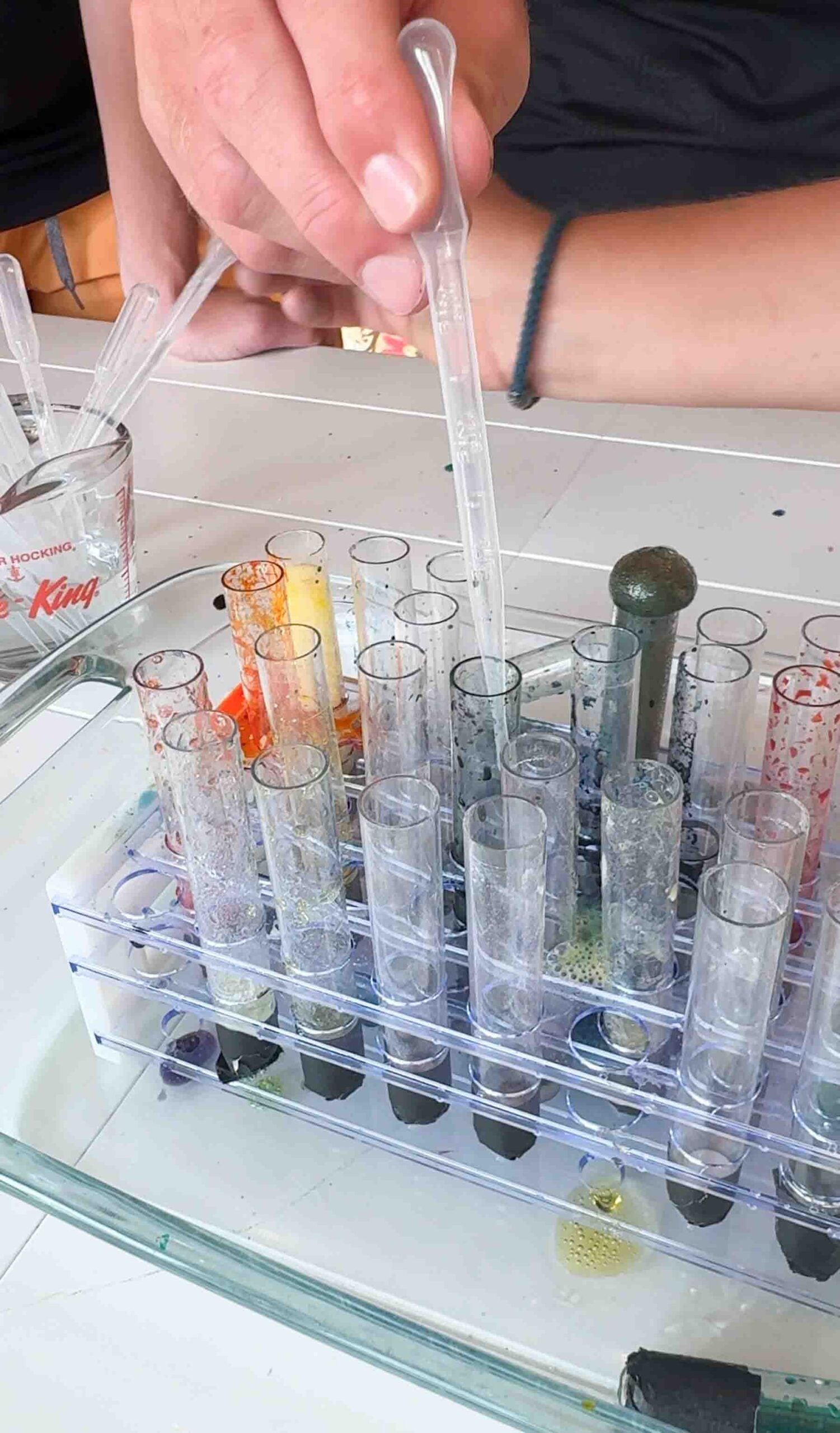 person putting vinegar into a test tube